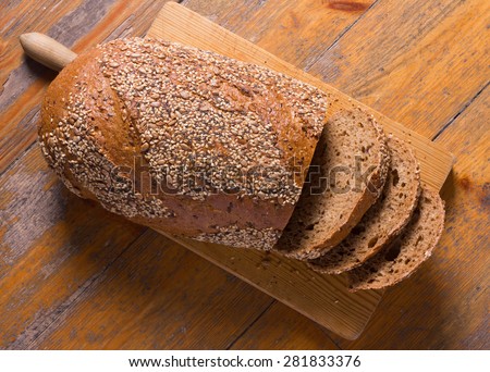Whole wheat bread with seeds on a cutting board.