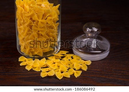 Macro image of raw pasta in glass jar on wooden background