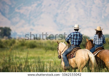 Similar – Image, Stock Photo A couple is horse riding on a meadow facing the distance. Romantic and active outdoor date. Autumn landscape, with young couple enjoying a horse riding. Overcast weather, beautiful horses.