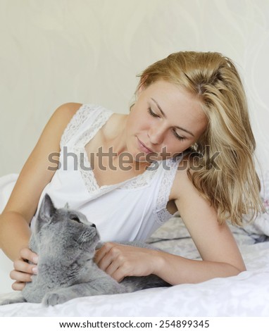 Young beautiful woman with british cat on the bed