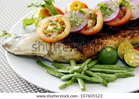 Close-up of a grilled milk fish with vegetable garnishing