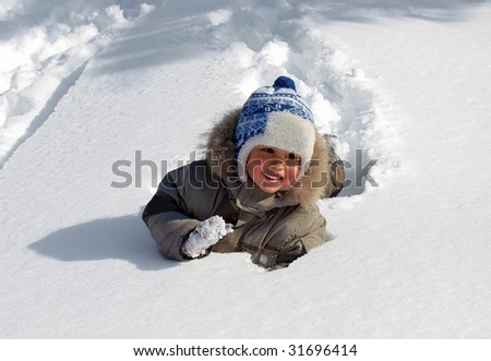 Funny little boy playing in snow, outdoors in winter.