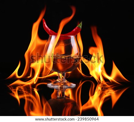 Hot chili pepper in a  Brandy glass with a fire on a black background