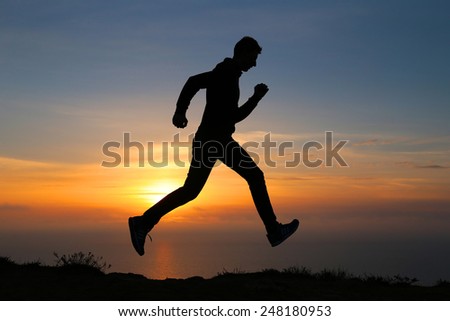 Silhouette of running man against the colorful sky. Silhouette of running man on sunset fiery background
