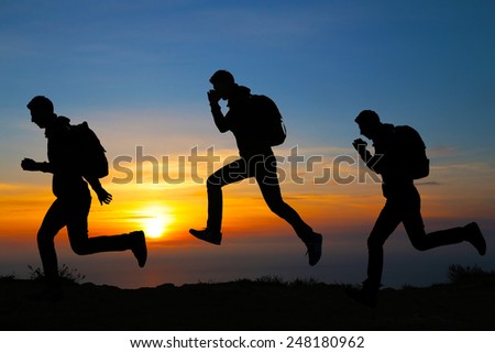 Silhouette of running men against the colorful sky. Silhouette of running man on sunset fiery background