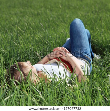 Attractive young woman taking a nap on green meadow.