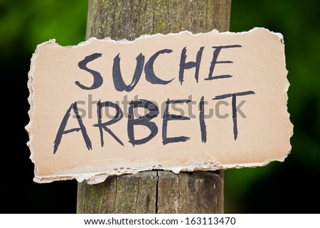 Cardboard sign showing the german term Suche Arbeit. English translation: looking for a job