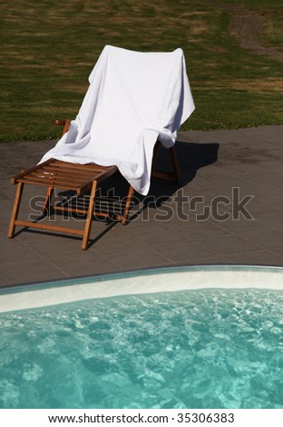 A standard deck chair standing next to a swimming pool.