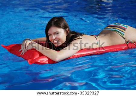 A very attractive young woman taking a sunbath on her red air mattress
