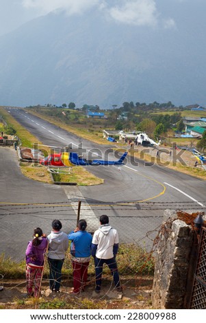 LUKLA, NEPAL - NOVEMBER 3: Nepali teenagers watch the landing of mountain helicopter in \