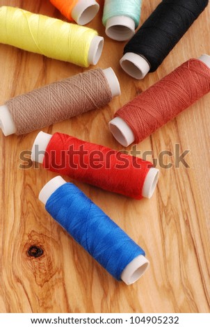 colored cotton reels on wooden table photographed up close