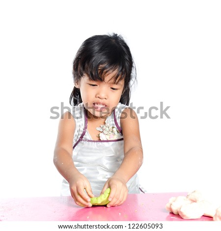 Little girl makes play dough on white background.