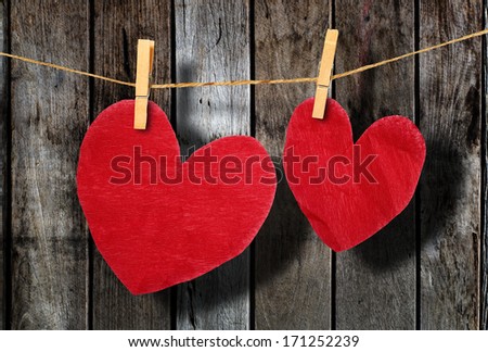 Red heart  hanging on clothesline on wood background.