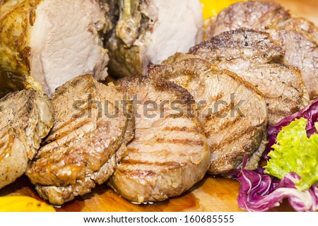 loin and steak cooked on a grill with vegetables