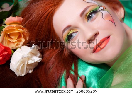Portrait of beautiful red-haired girl with flowers and bright makeup