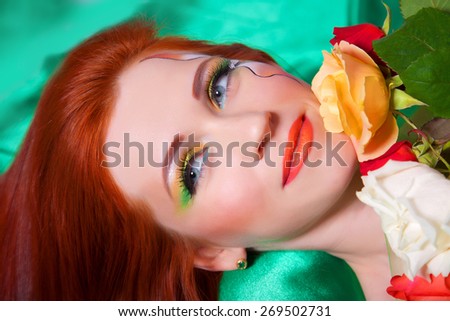 Portrait of beautiful red-haired girl with flowers and bright makeup