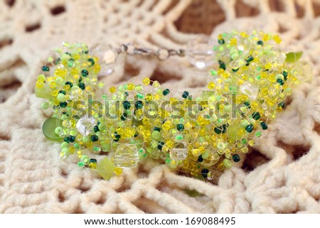 handmade bracelet of yellow and green glass beads from India on knitted background