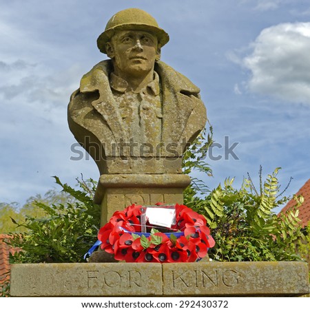 Weathered World War I war memorial with remembrance poppies in the village of Kilburn in North Yorkshire, England