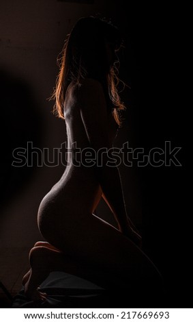 Sexy woman lies, darkness, light contours, wet skin