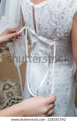 Bride dressing gown. bride preparing for a wedding. bride is getting dressed in the room. brunette young bride prepare for the event by makeup artist.