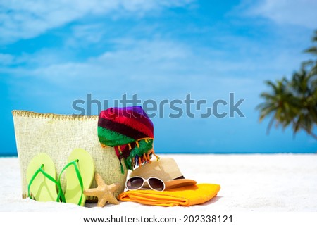 Summer beach bag with starfish,towel,sunglasses and flip flops on sandy beach