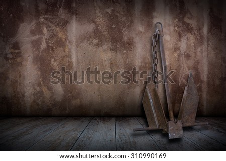 Old rusty boat anchor in plaster walls and old wooden floors, Vintage style.