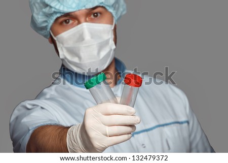 young doctor with container for analysis. with emotions under the mask