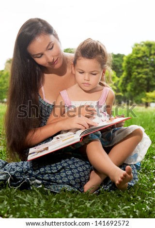 Mom and daughter reading a book in the park