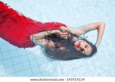 Female in a red dress swimming in the pool