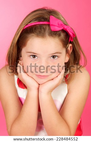 Cute eight year old girl portrait on a pink background