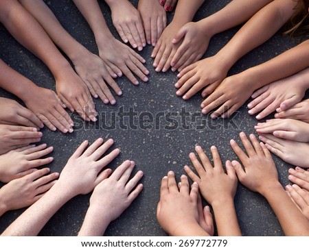 Large group of children\'s hands on the pavement outside leaving copy space in the middle.