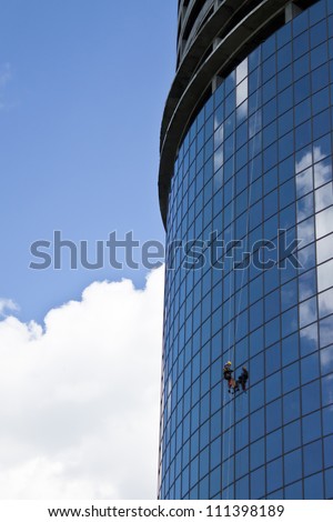 climber washes windows of office center