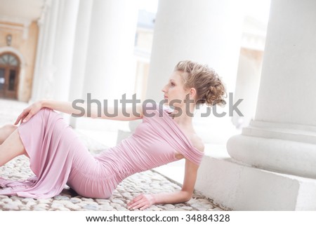 fashion shot of a young woman sitting near columns in old mansion