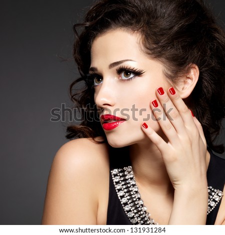 Pretty fashion model with red manicure and lips - Brunette woman on black background