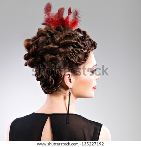 Beautiful adult woman with fashion hairstyle with red feather in hairs