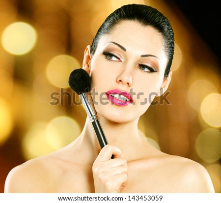 Portrait of  beautiful woman applying blusher on face using cosmetic brush