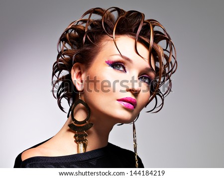 Beautiful woman with fashion creative  hairstyle and glamour makeup  posing at studio
