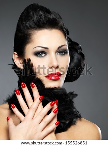 Beautiful fashion woman with red nails, creative hairstyle and makeup - Model posing in studio