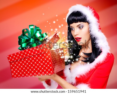 Photo of the surprised  snow maiden looks into the christmas box  with gift in it -  over creative background