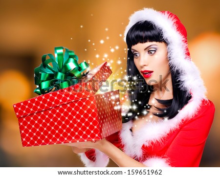 Photo of the surprised  snow maiden looks into the christmas box  with gift in it -  over creative background