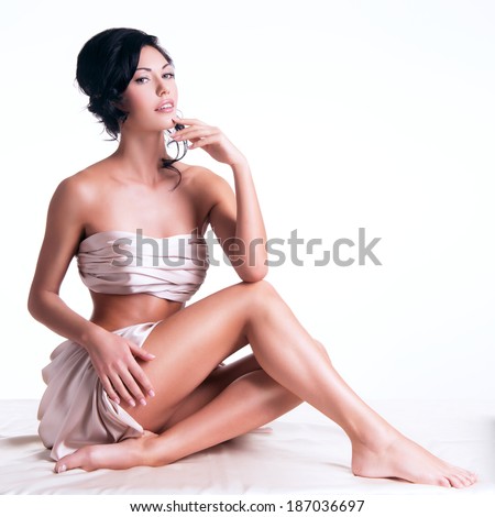 Sensual young woman with beautiful body in the beige silk over white background