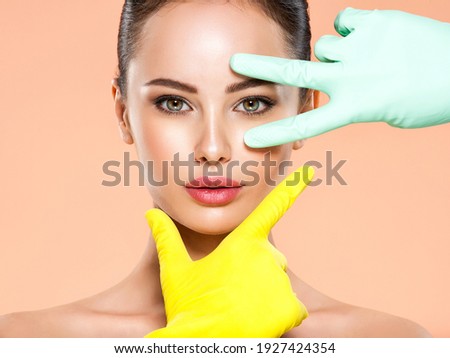 Face skin check before plastic surgery. Beautician touching young woman face. Doctor in medicine gloves checks a skin before plastic surgery. Beauty treatments. Colorful image