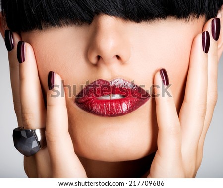 Closeup face of a woman with beautiful sexy red lips and dark nails - studio