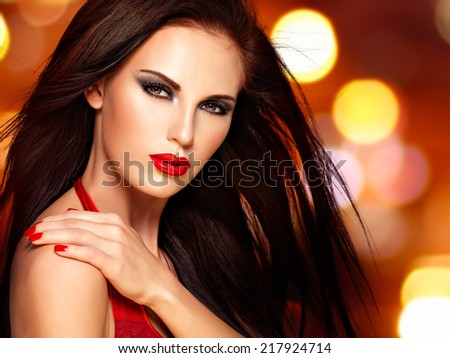 Beautiful brunette woman with red lips and nails.  Face of a pretty girl over night lights  background