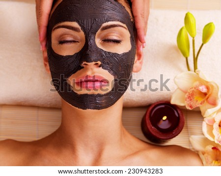 Cosmetologist doing massage on the woman\'s face  in sap salon. Female with scrub cosmetic mask on face.