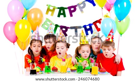 Group of kids in colorful shirts blowing candles at the birthday party - isolated on a white.