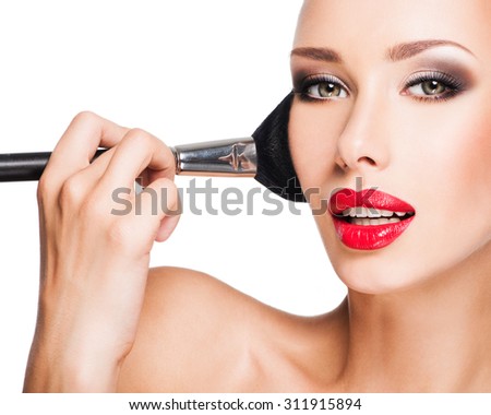 Closeup portrait of a woman  applying dry cosmetic tonal foundation  on the face using makeup brush.