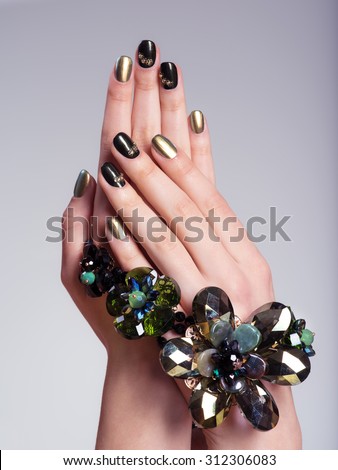 Beautiful woman\'s nails with  creative manicure and jewelry. Studio image