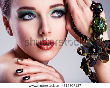 Beautiful woman face with fashion green make-up and jewelry on hand