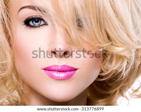 Beautiful woman with long blond curly hair. Portrait of fashion model with bright makeup. Isolated on white